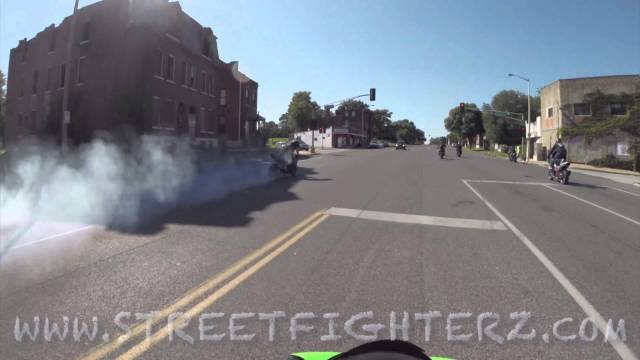 Motorcycles do burnouts in oncoming traffic through cars.