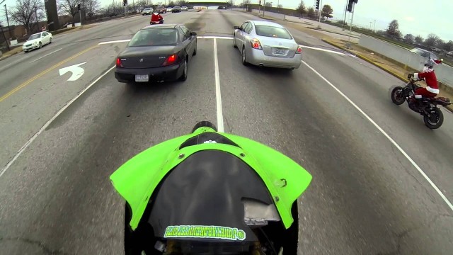 Motorcycle splits cars in a wheelie while running red light